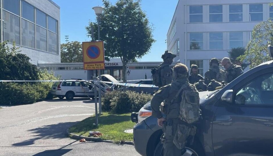 Poliserna i ett planeringsmöte. I bakgrunden ses bilar som 'kolliderat' inne på skolgården, som en del i övningen.