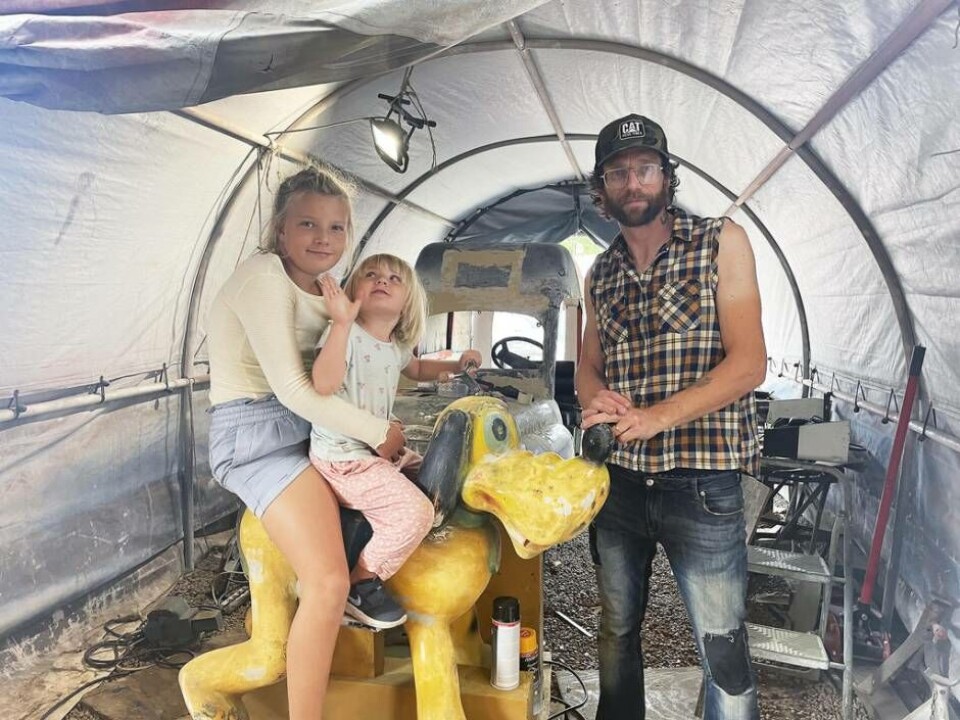 Jonas Henriksson med döttrarna i det garagetält där han jobbar med att renovera den gamla Pluto-karusellen som ska stå på Lasse Åbergs lekpark i Bålsta. Foto: Jonas Edberg