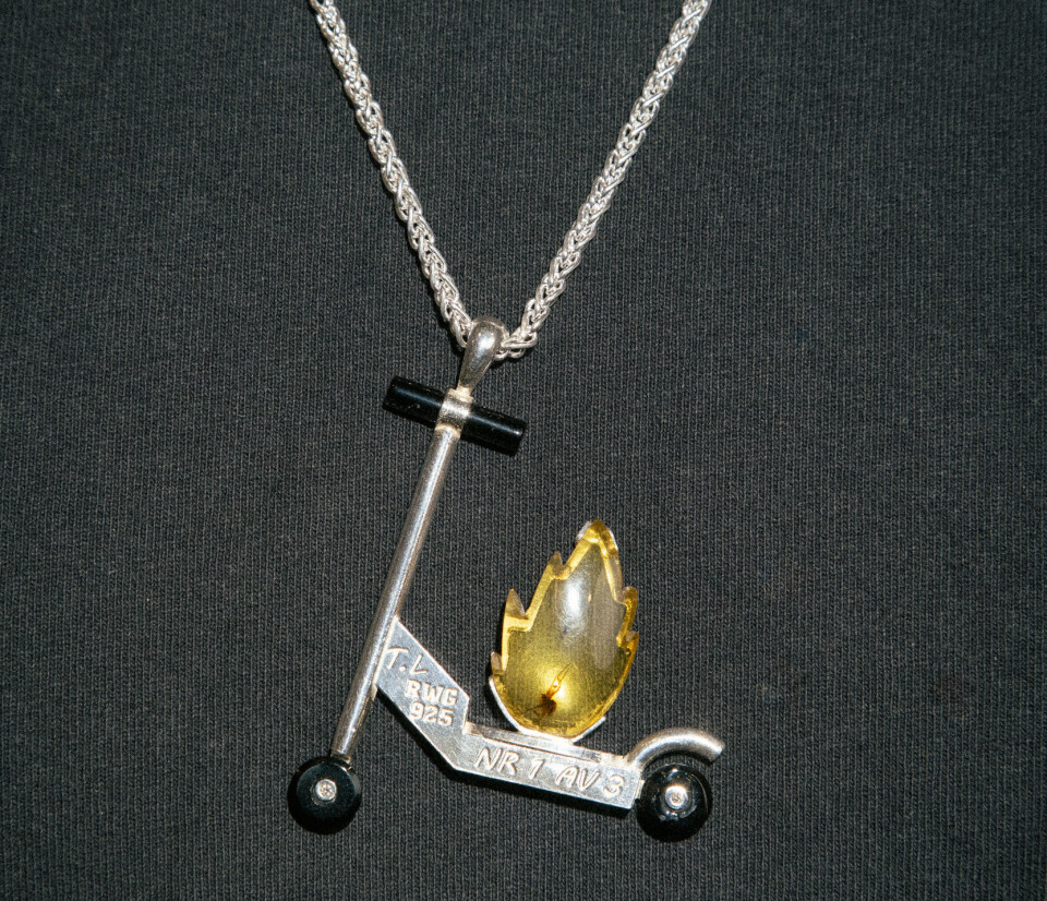 Smycke. En brinnande elsparkcykel i silver, onyx, diamant och bärnsten.